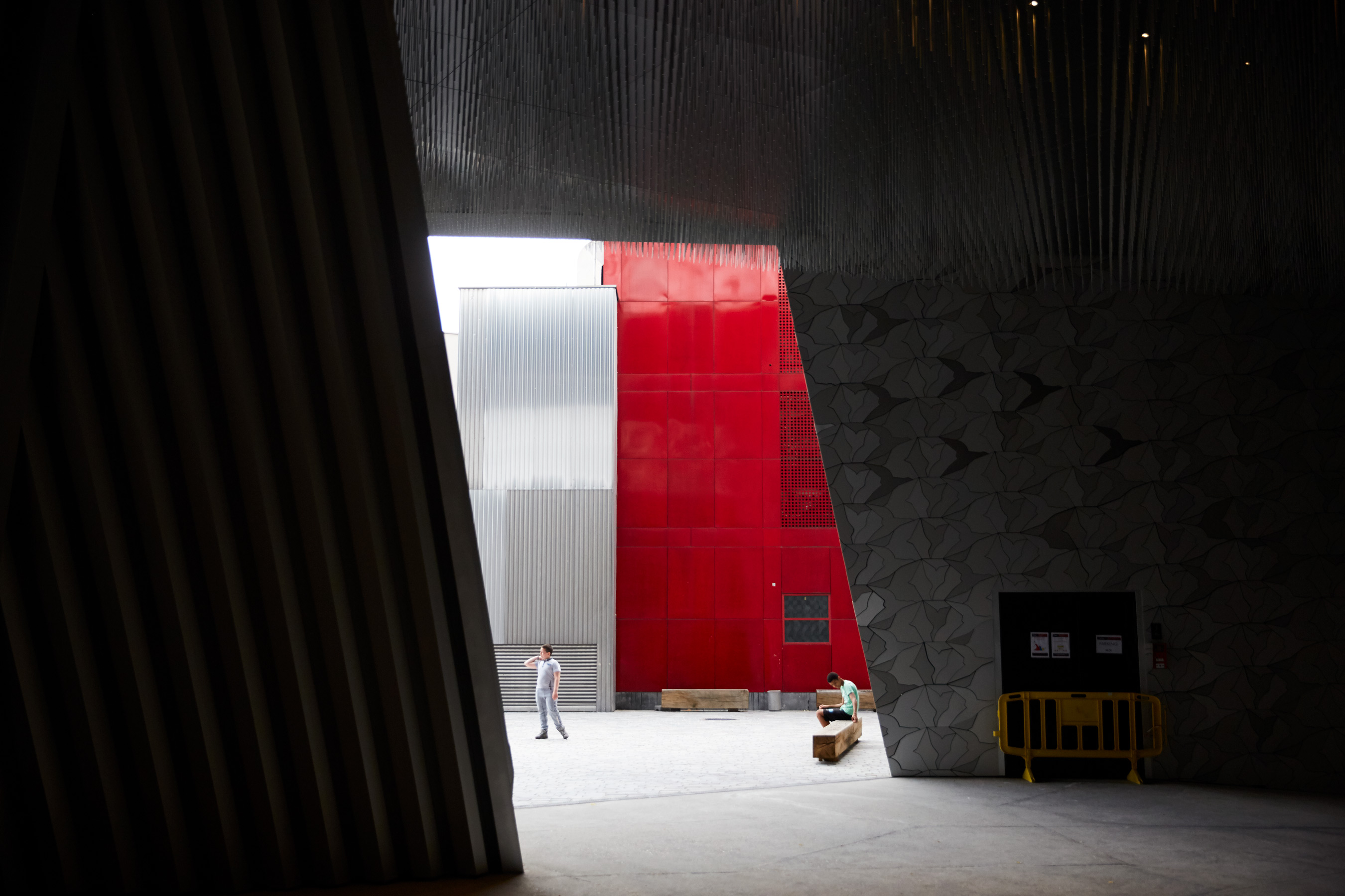 two boys at Paris Philharmonie building in front of red wall 