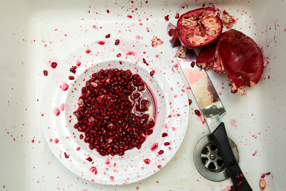 pomegranate seeds in sink with knife