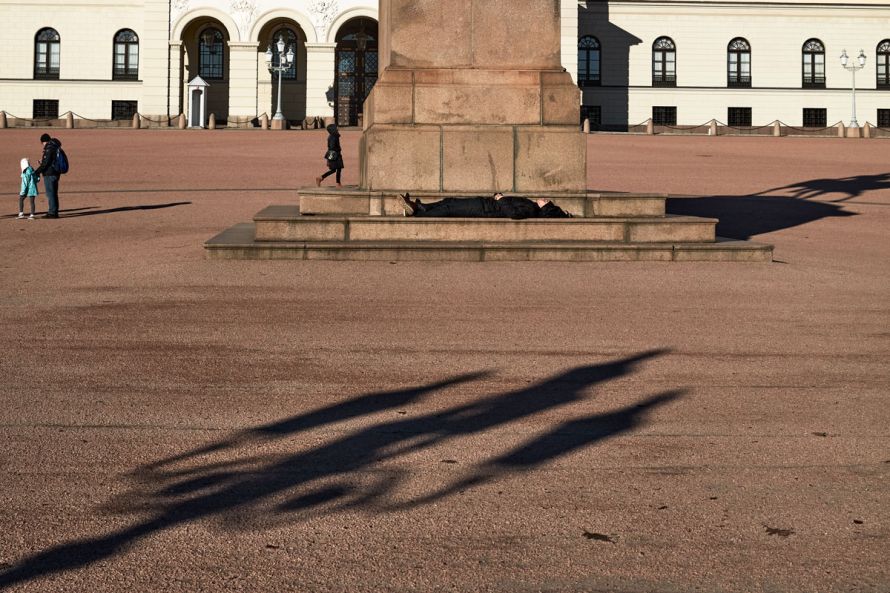 man sleeping on bench in front of the Royal Castle in Oslo
